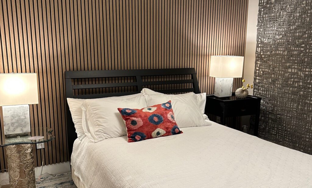 Tight wooden slats and artwork hanging on different walls of a bedroom to illustrate unique accent wall ideas.